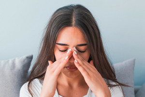 Woman grabs the top of her nose with both hands