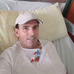 Mann mit Cap liegt lächelnd im Krankenhausbett