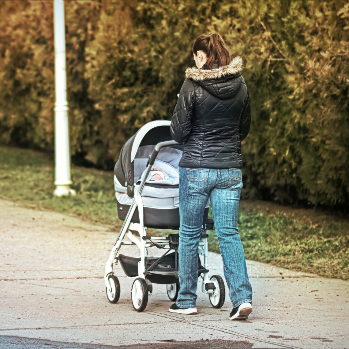 Newborn has a sniffle: Go for a walk Young woman with pram walking from behind