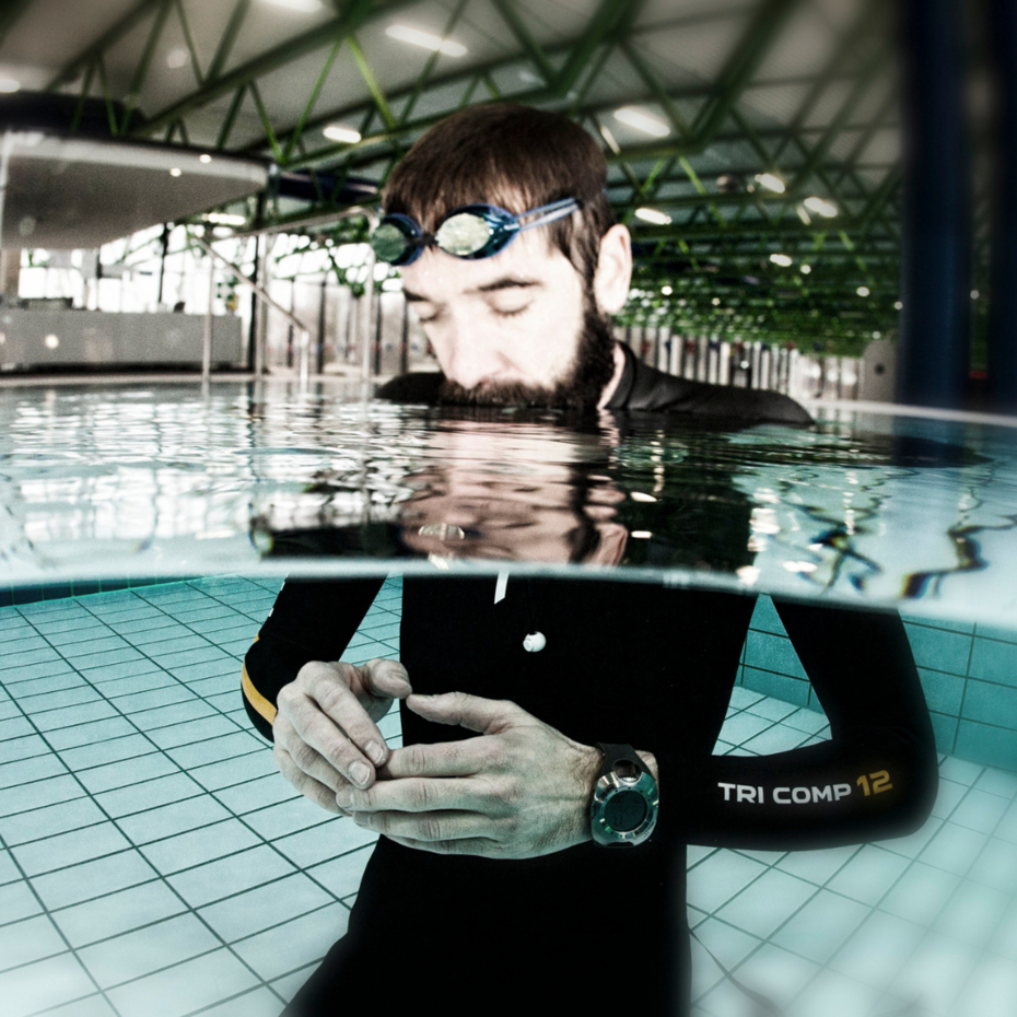 Nik Linder im Taucheranzug steht im Schwimmbecken, den Kopf über Wasser, und konzentriert sich