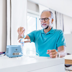 Elderly man filling the PARI COMPACT2 inhalation device with saline solution