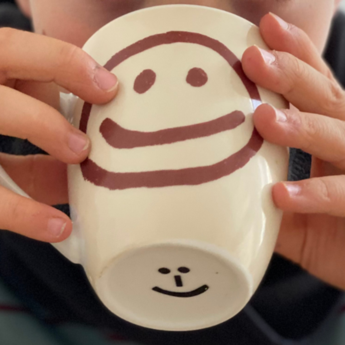 Schmerzhafter Husten: Warmen Tee trinken Nahaufnahme einer Tasse, die ein Kind in den Händen hält