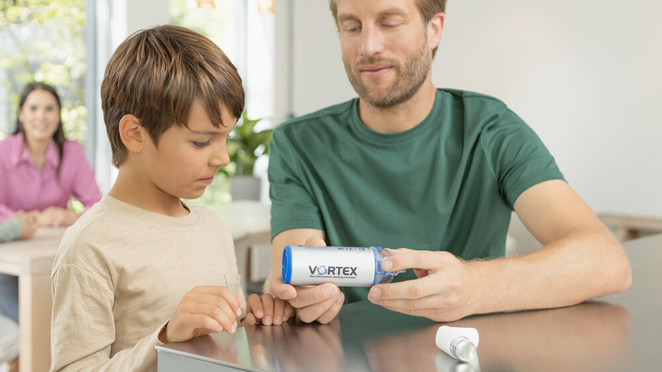 Father sits with his son at the kitchen table and shows him the VORTEX spacer