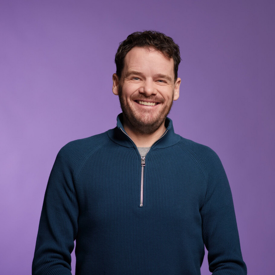 Half close-up of a smiling man against a purple background 
