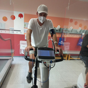 Mann sitzt mit Maske auf Hometrainer und trainiert