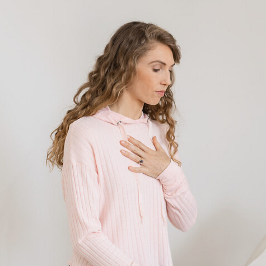 Junge Frau räuspert sich und hält sich dabei die Brust