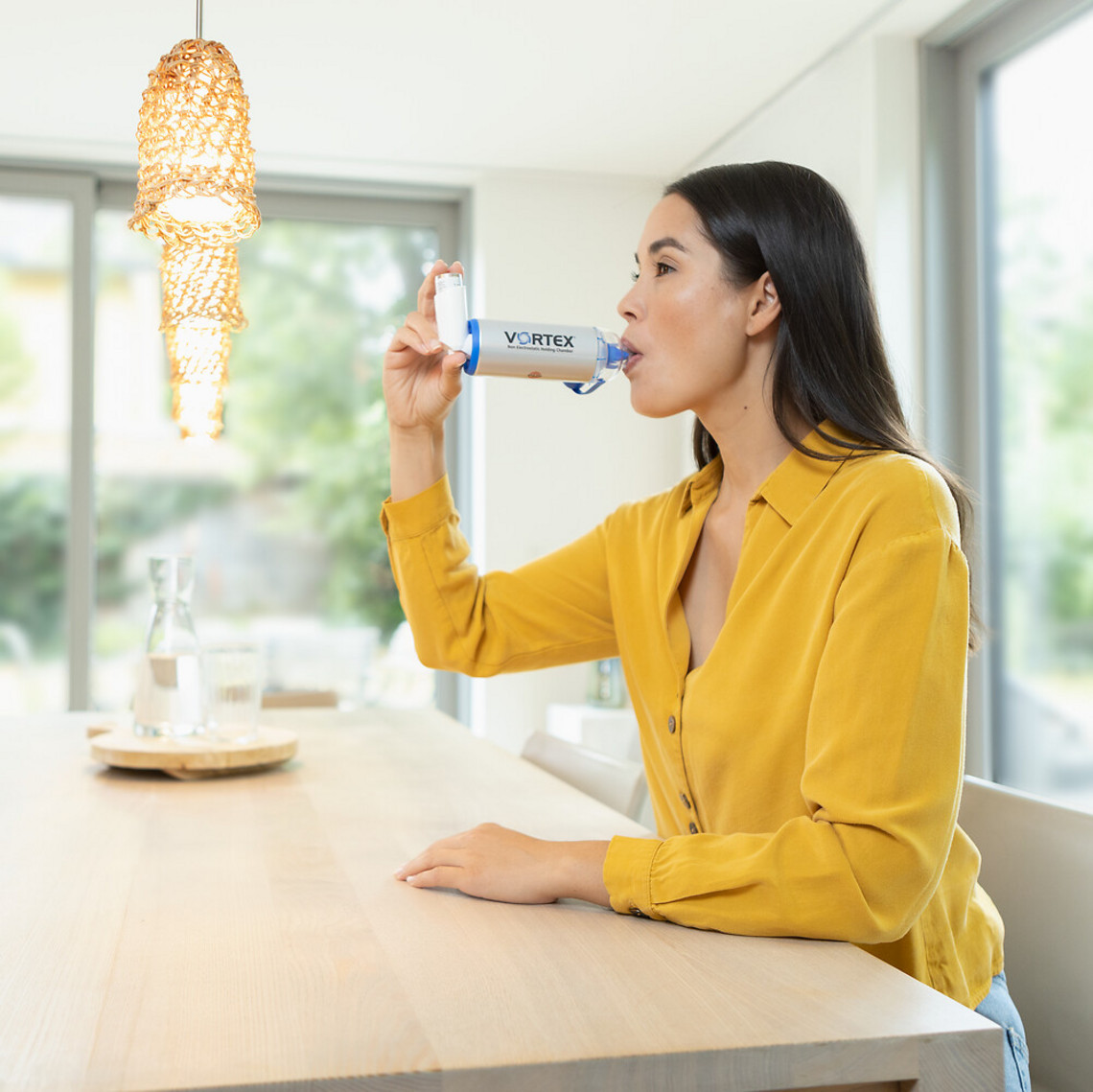 Young woman inhaling asthma spray with VORTEX spacer