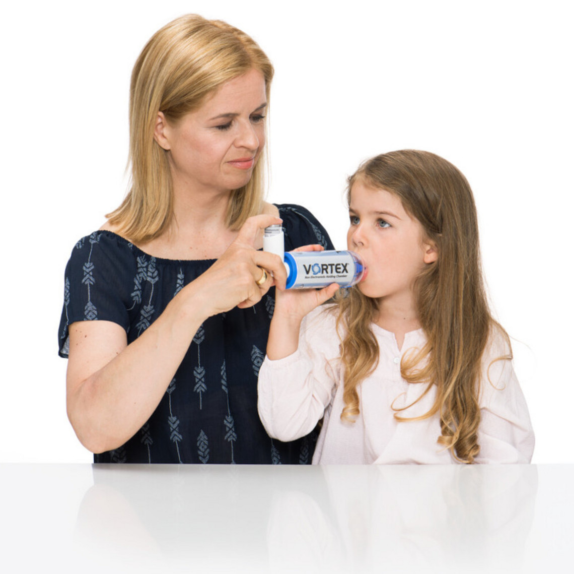 Mutter hilft Tochter bei der Inhalation von Asthmaspray mit Inhalierhilfe