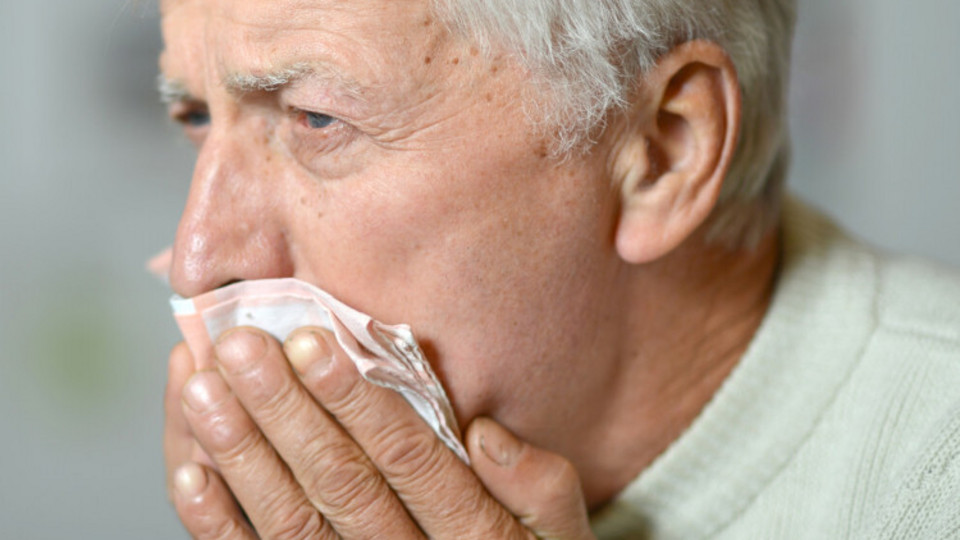 Älterer Mann hustet in Taschentuch