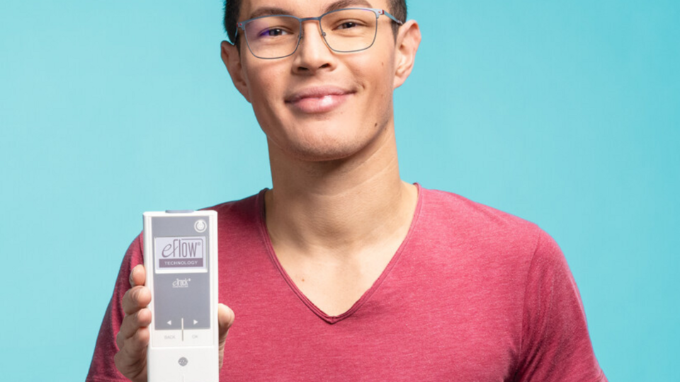 Junger Mann in Halbnahaufnahme, er hält den eTrack Controller zum eFlow®rapid Inhalationssystem in die Kamera