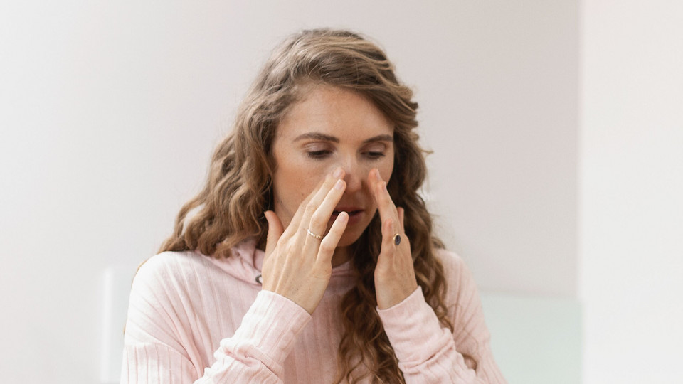 Young woman holding both hands at the top of her nose
