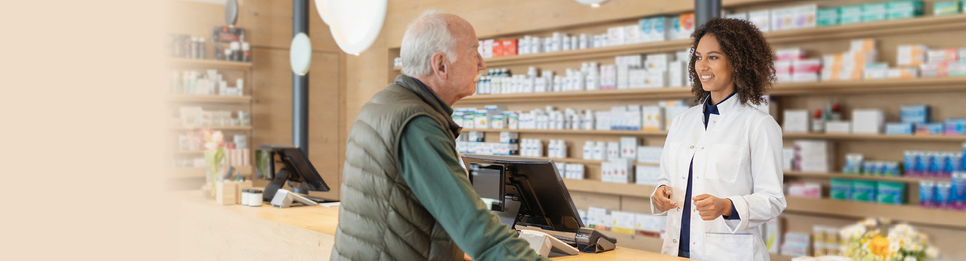 Eine Apothekerin berät in einer Apotheke einen älteren Kunden