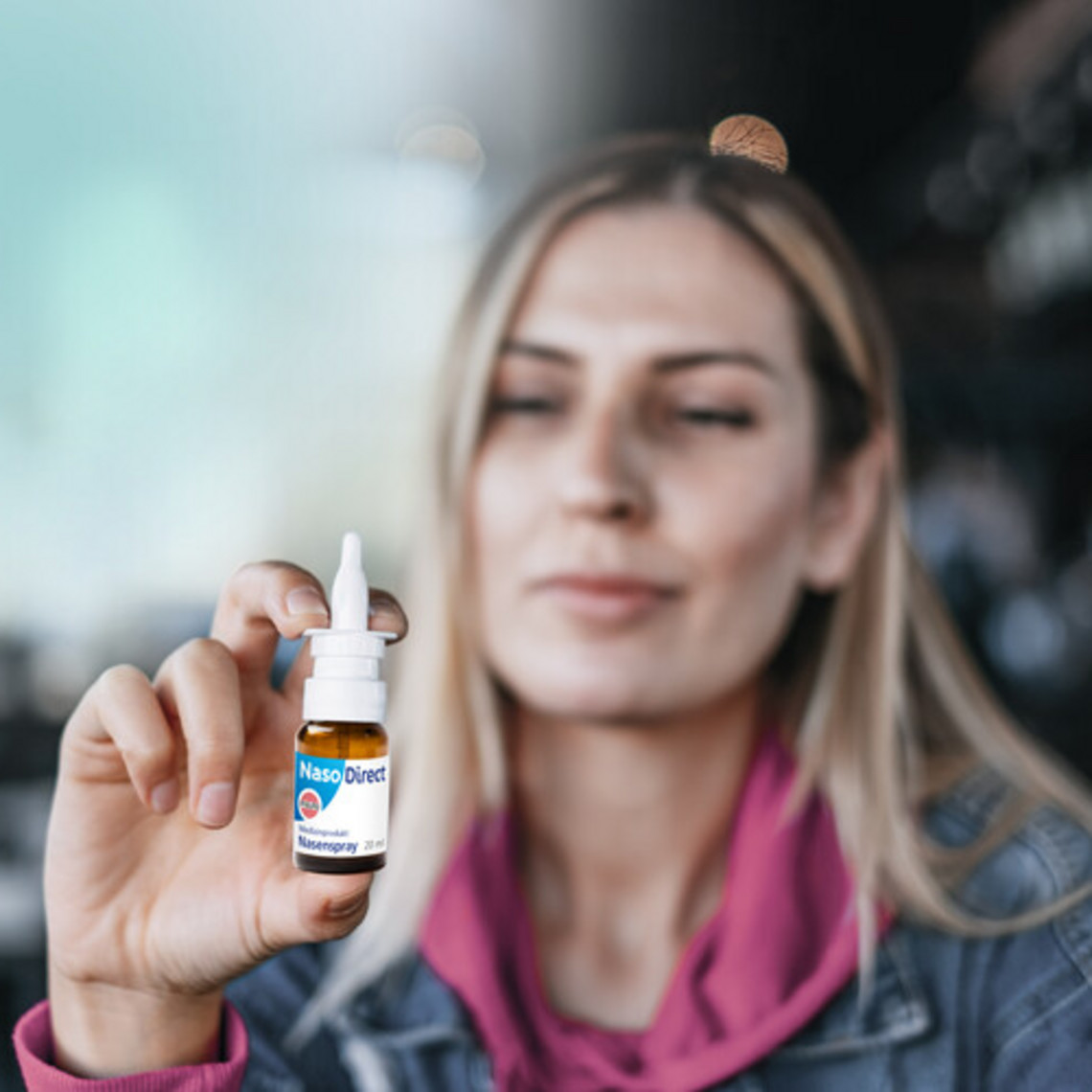 Frau hält NasoDirect Nasenspray in die Kamera