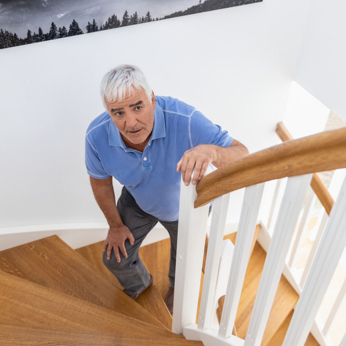 Old man standing on stairs and holding onto the railing