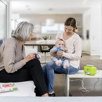 Ein Baby sitzt auf dem Schoß der Mutter und inhaliert mit dem PARI BOY Junior. Die Oma sitzt daneben und schaut zu.