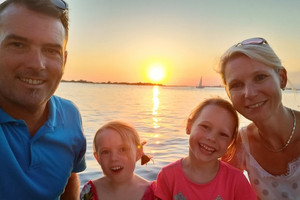 Vater, Mutter und zwei Töchter am Meer während Sonnenuntergang