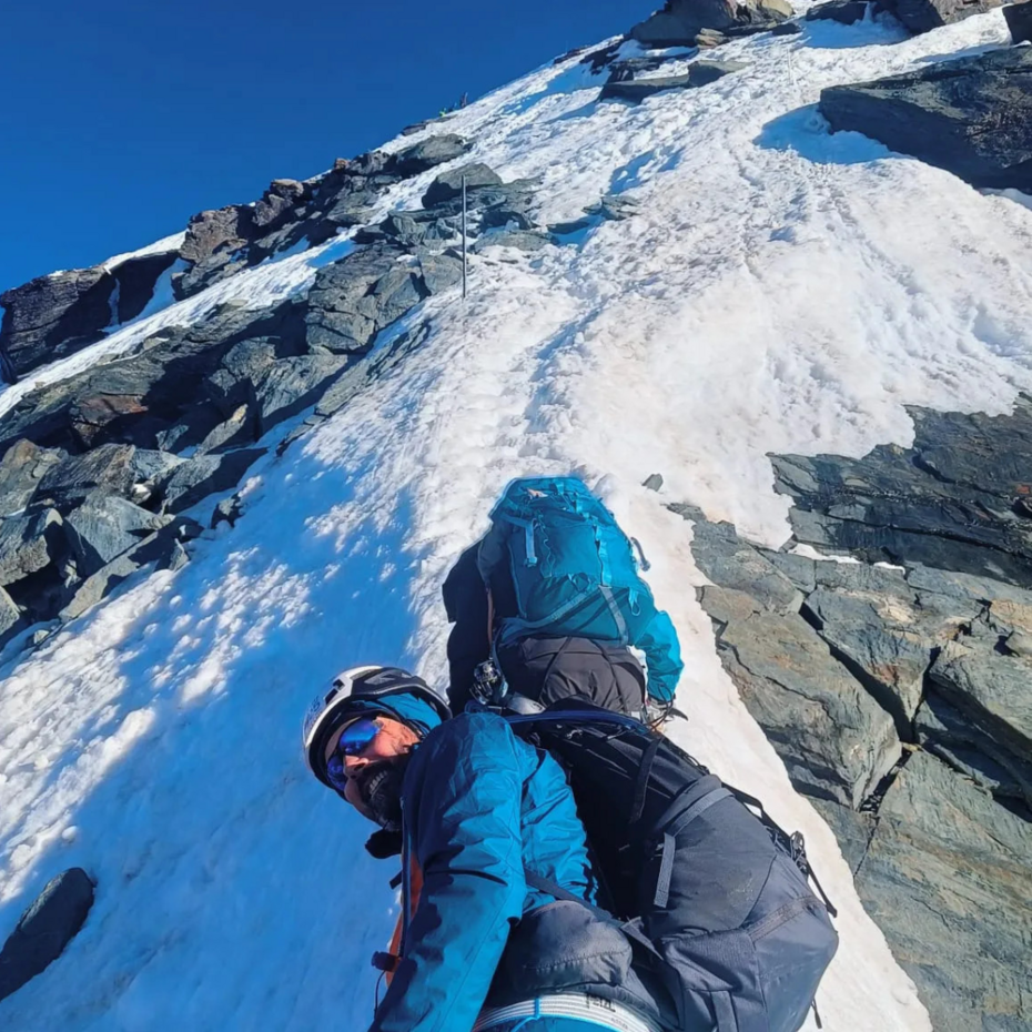 Bergwanderer von unten aufgenommen an einem schneebedeckten Hang
