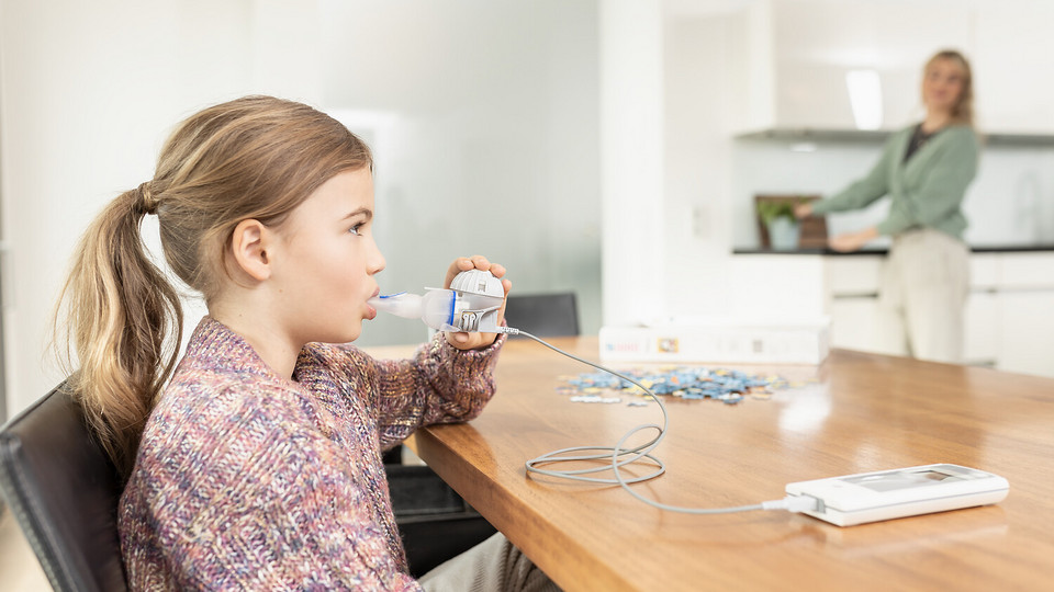 Young girl sits on the table using the eFlow®rapid nebuliser system