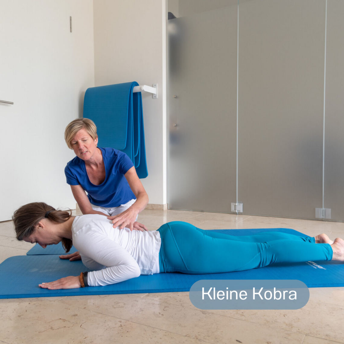 Übungen, um die Lunge von Sekret zu befreien: Kleine Kobra Junge Frau liegt auf einer Matte am Boden und macht die Übung Kleine Kobra, während die Physiotherapeutin sie anleitet