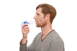 Man inhales with nebulizer with attached PEP system