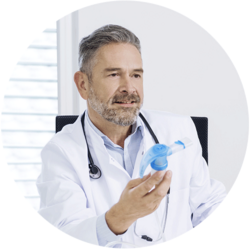 Arzt in weißem Kittel hält ein Inhalationsgerät Arzt in weißem Kittel hält ein Inhalationsgerät und erklärt dessen Gebrauch in einer Arztpraxis.