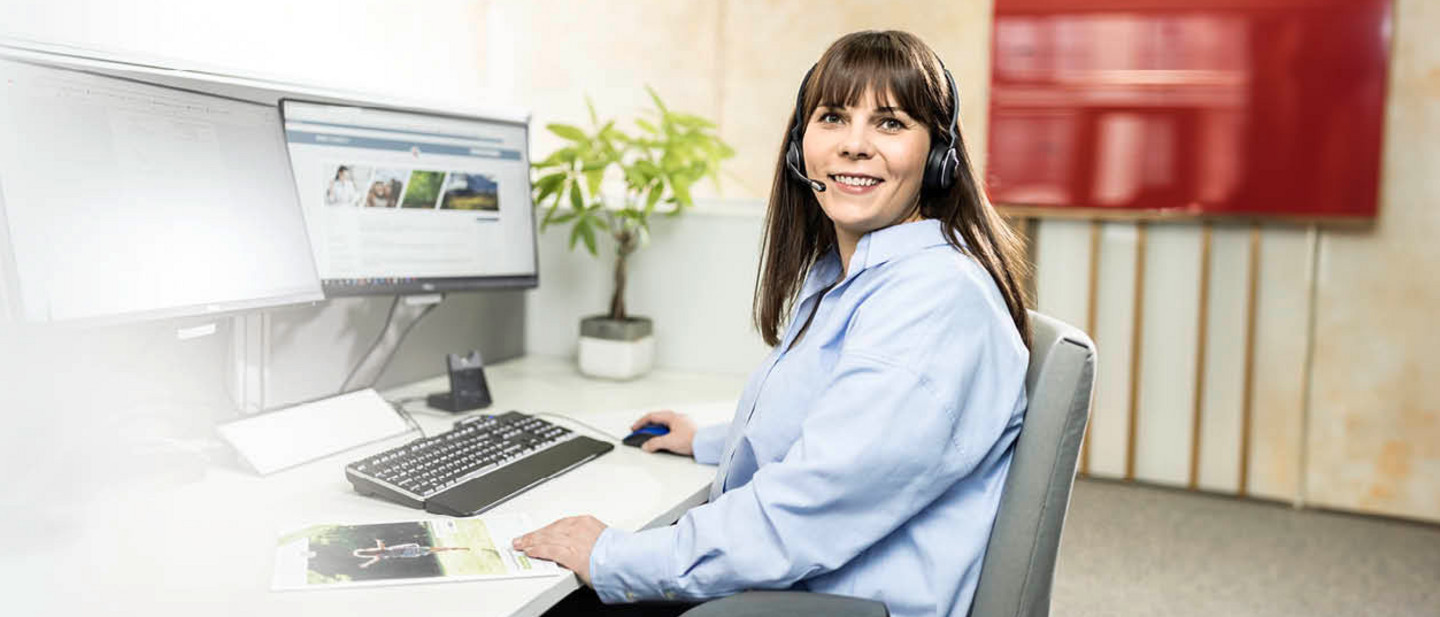 A PARI service employee sits in front of a computer with a headset and advises a customer over the phone