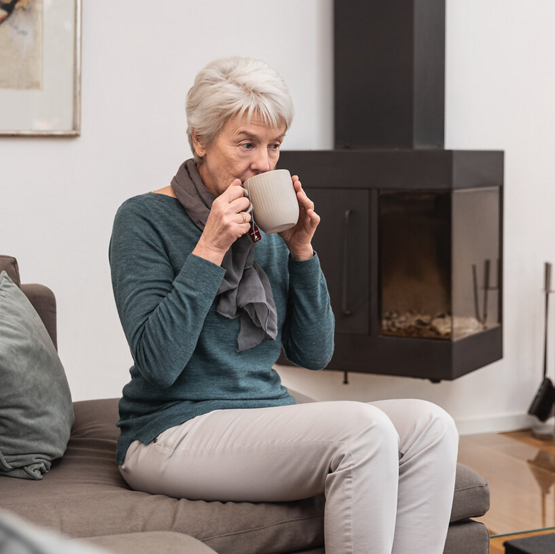 Eldery woman sitting in the living room while drinking a cup of tea