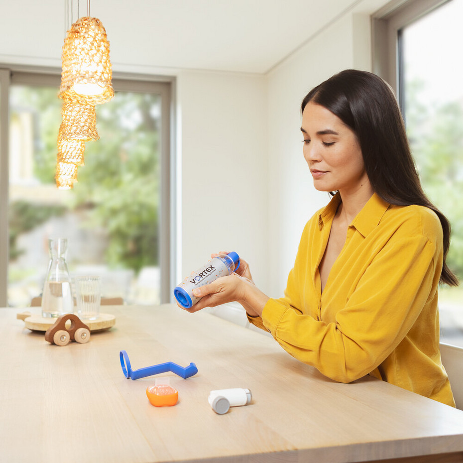 Reinigung der Inhalierhilfe: Auseinanderbauen Junge Frau sitzt an Wohnzimmertisch und baut VORTEX Inhalierhilfe auseinander