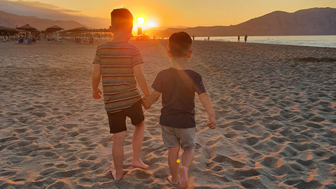 Urlaub mit Asthma: Erfahrungen einer Familie Zwei Jungs spazieren Sonnenuntergang am Strand entgegen