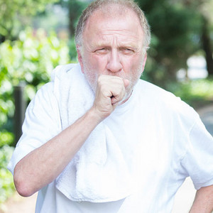 Older man in sportswear coughs hard into his fist