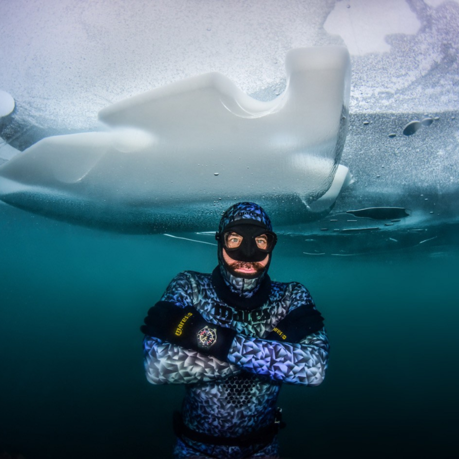 Apnoetaucher im Wasser, über ihm eine Eisdecke