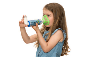 Kind inhaliert Asthmaspray mit Hilfe eines Spacer und einer Maske