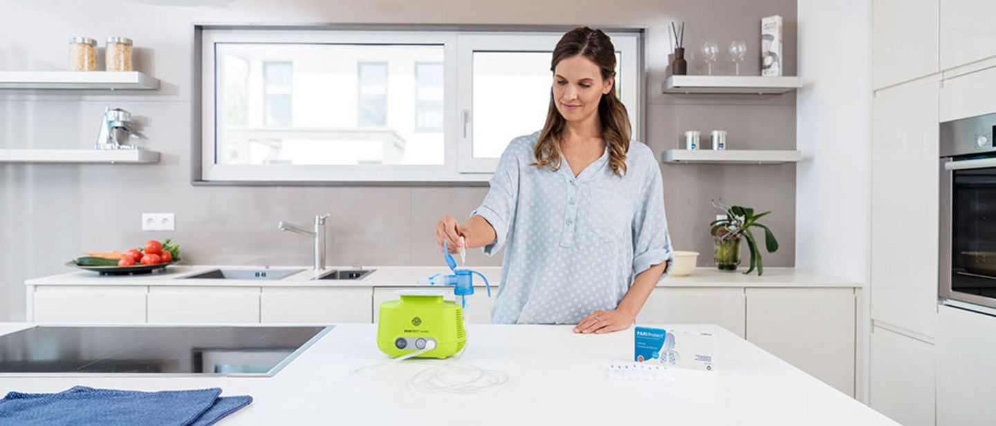 Filling a nebuliser with PARI Protect inhalation solution A woman fills the nebuliser of a PARI BOY Junior with PARI Protect inhalation solution in a modern kitchen.