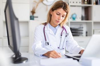 Young doctor looks into patient file at her desk