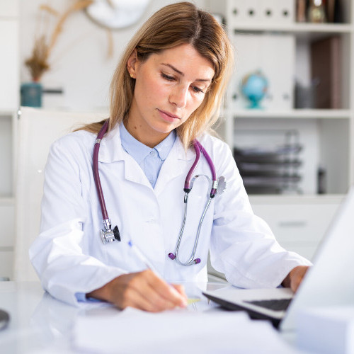 Junge Ärztin schaut an ihrem Schreibtisch in Akte