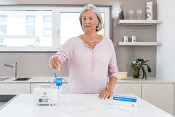 Frau füllt in der Küche Inhalationslösung in Inhalationsgerät