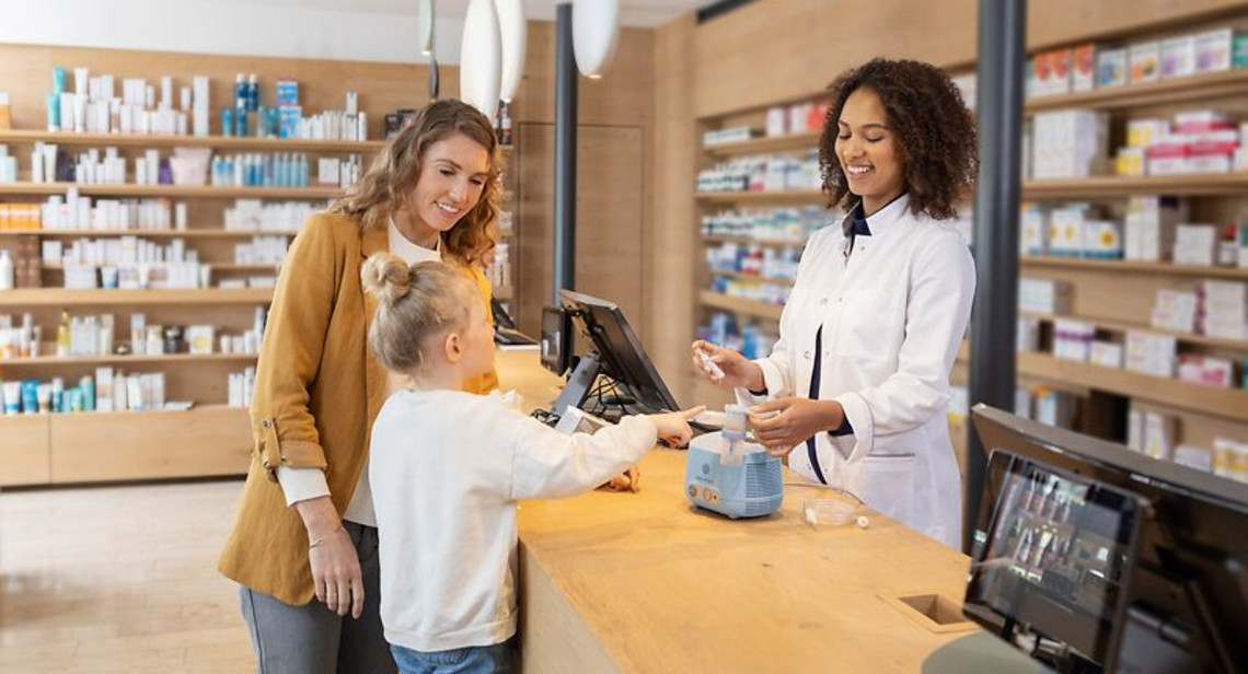 Eine Apothkerin erklärt den PARI COMPACT2 einer jungen Mutter und ihrem Kind Eine Apothkerin erklärt den PARI COMPACT2 einer jungen Mutter und ihrem Kind