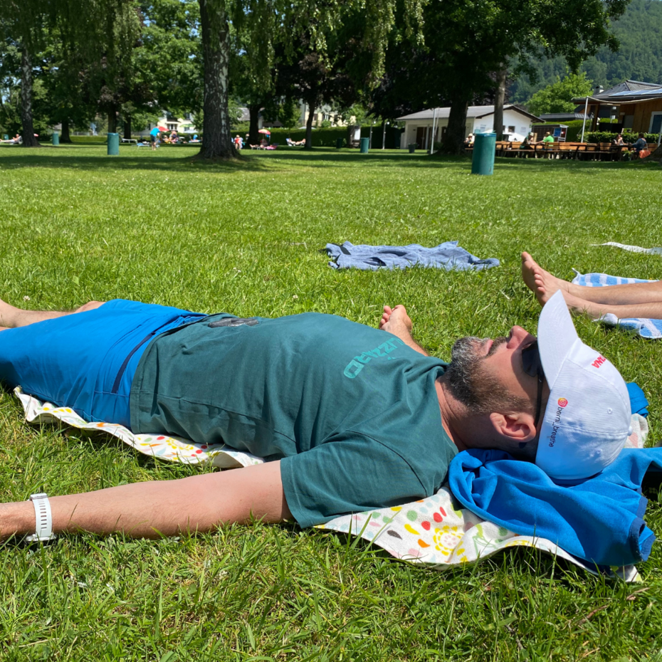 Mann liegt entspannt auf einer Wiese auf dem Rücken