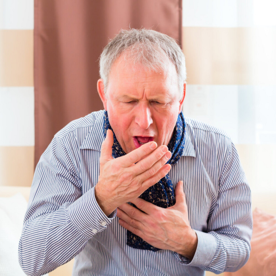 Coughing elderly man holds one hand to his chest, one in front of his mouth