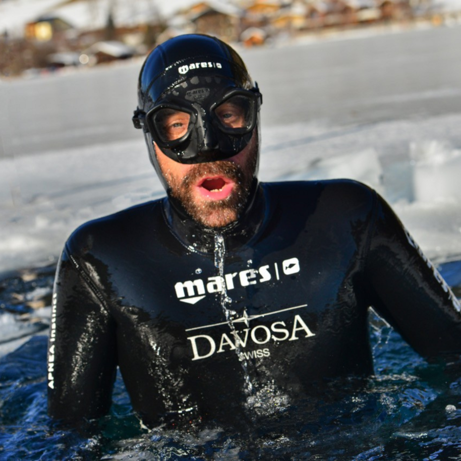 Taucher taucht aus einem Loch im Eis wieder auf