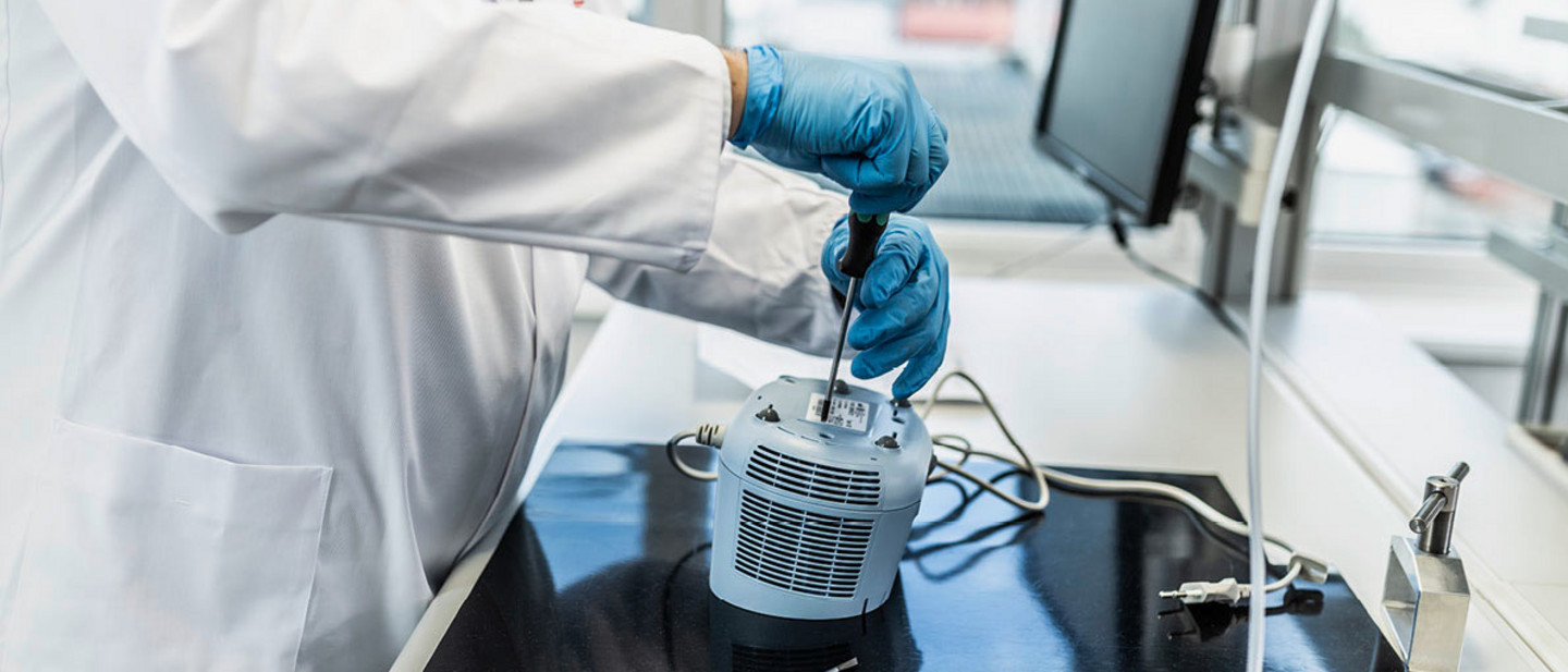 Ein Service-Techniker von PARI öffnet mit einem Schraubendreher das Gehäuse eines PARI Compact2, um es zu überprüfen