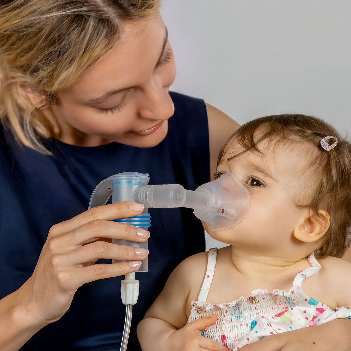 Mutter hat Baby auf dem Schoß und inhaliert mit ihm mit einem PARI LC SPRINT Vernebler