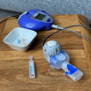 Inhalationsgerät mit Controller, Inhalationslösung und Schale mit Tabletten auf einem Tischchen