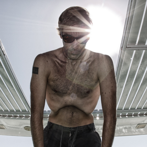 Mann stützt sich am Beckenrand ab, er konzentriert sich und atmet tief ein, Bauch nach innen gewölbt