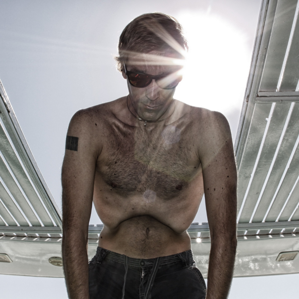 Mann stützt sich am Beckenrand ab, er konzentriert sich und atmet tief ein, Bauch nach innen gewölbt