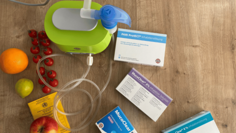 Inhalationsgerät, Inhalationslösungen, Obst und ein Impfpass liegen auf einem Tisch