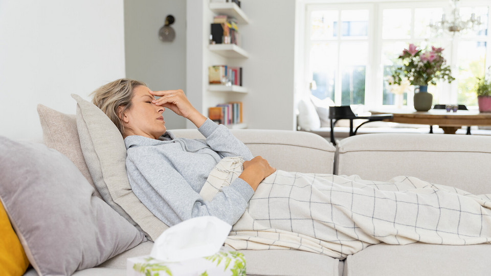 Coughing worse at night and in bed: Why asthma symptoms are worse in the evening Young woman lying on the couch holding her hand to her nose