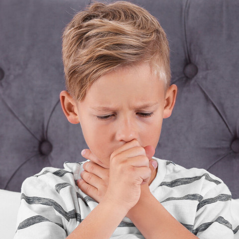 Kind mit Asthmaanfall hält sich eine Hand an den Hals, die andere vor den Mund