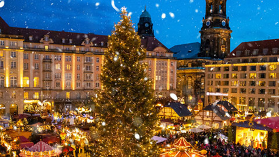 Bild eines von vielen Lichtern beleuchteten Weihnachtsmarktes in einer Stadt