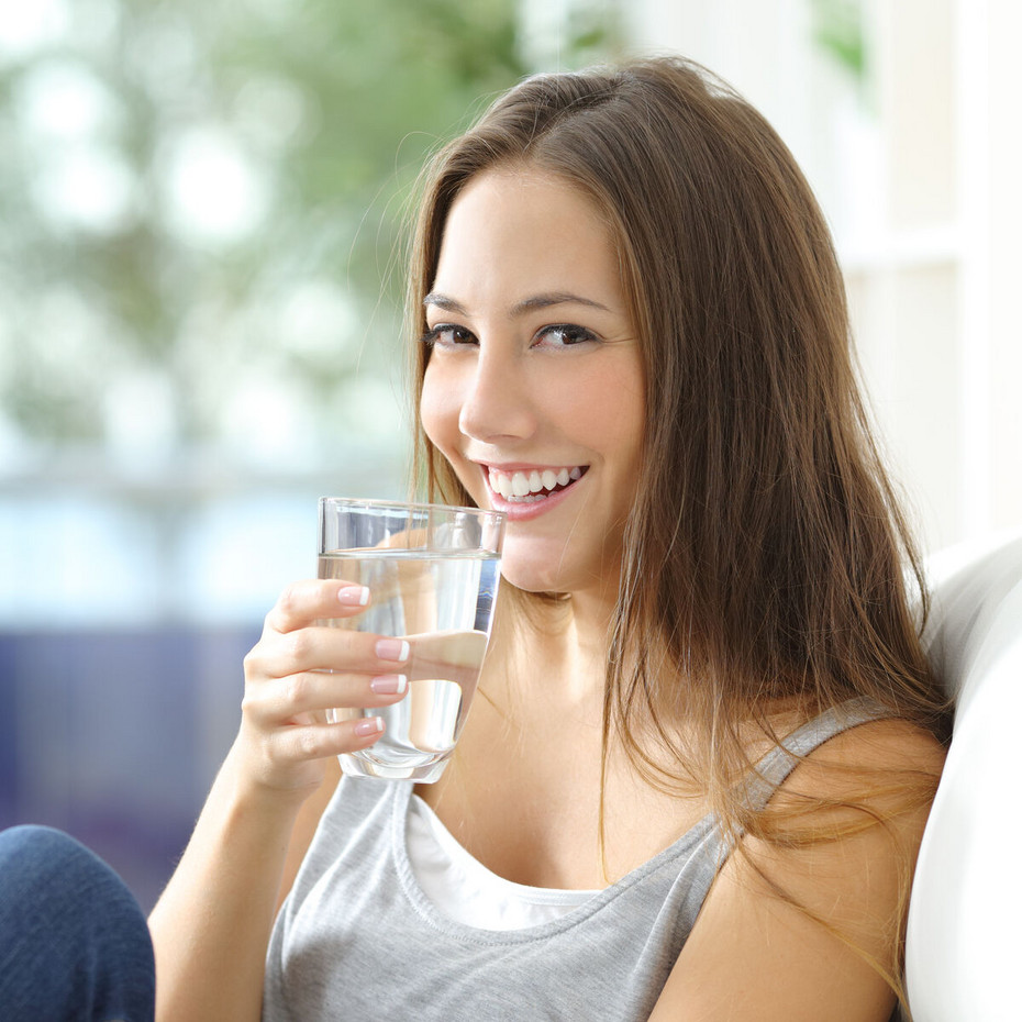 Calming irritated bronchial tubes: Keep mucous membranes moist Young woman in medium close-up, smiling and holding a glass of water in her hand